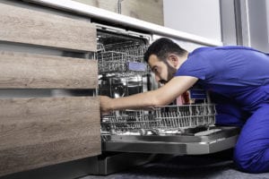 Man repairing dishwasher. Read to learn WHY WON’T MY DISHWASHER DRAIN?