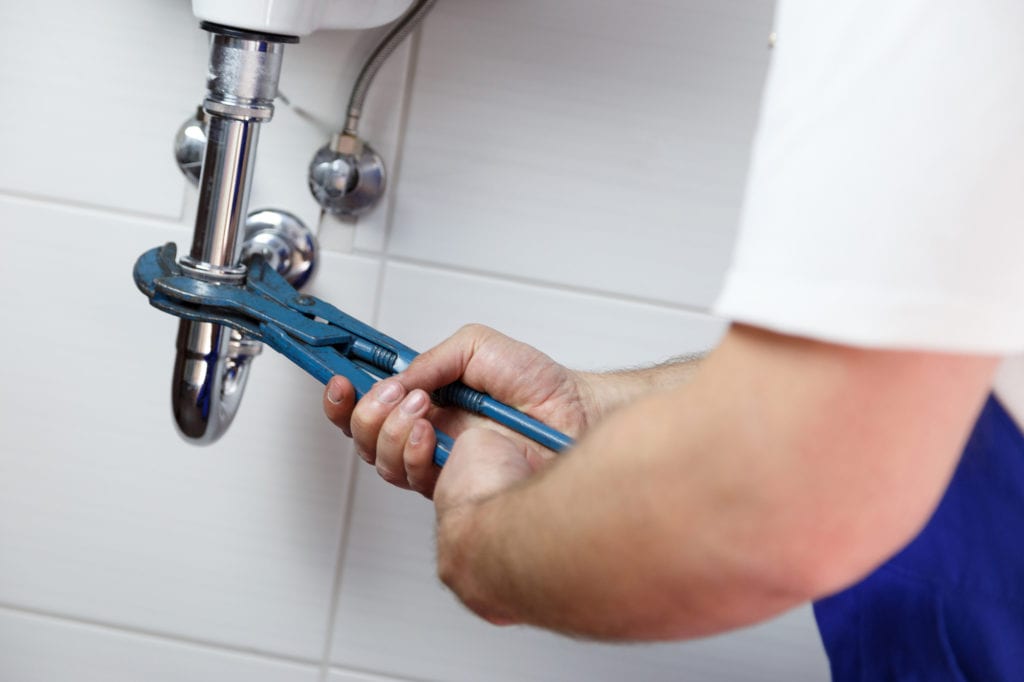 HOW TO UNCLOG A BATHROOM SINK, plumber with wrench under sink